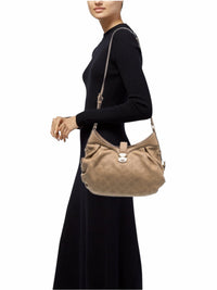 YoloLuxe Handbags beige perforated leather hobo bag with gold hardware worn on the shoulder by a model in black.