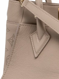 YoloLuxe Handbags taupe leather handbag with perforated Monogram side detail and gold-tone hardware.